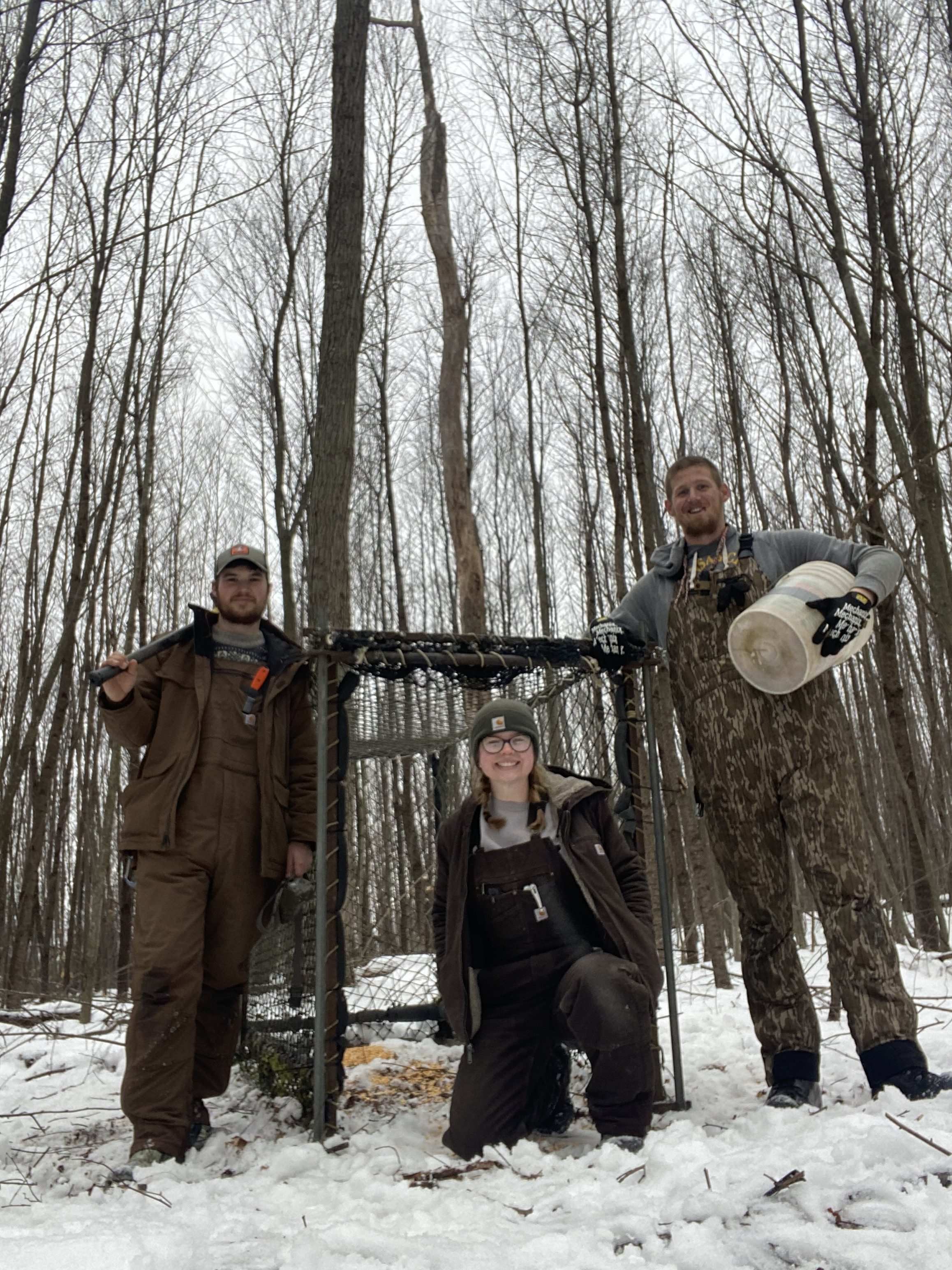 3 crew members stand in front of a Clover Trap in the woods
