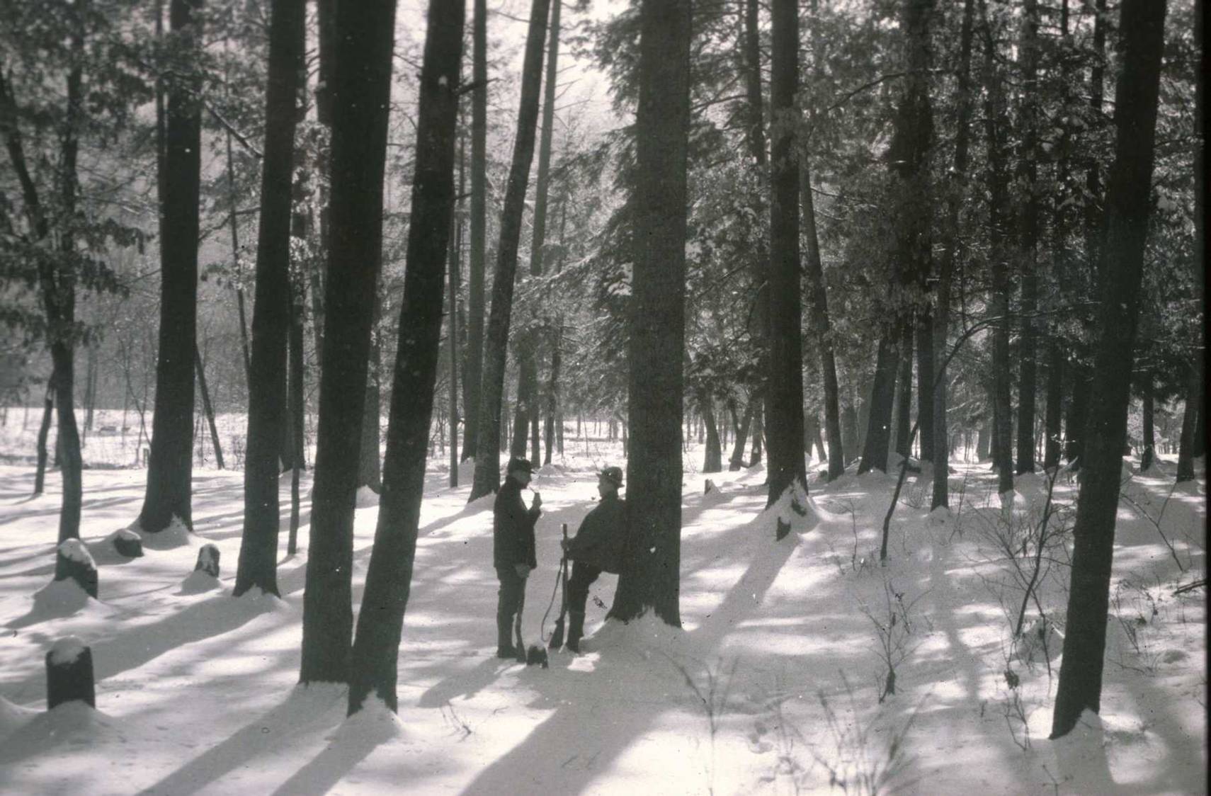 2 hunters standing in forest in snow - black and white photo