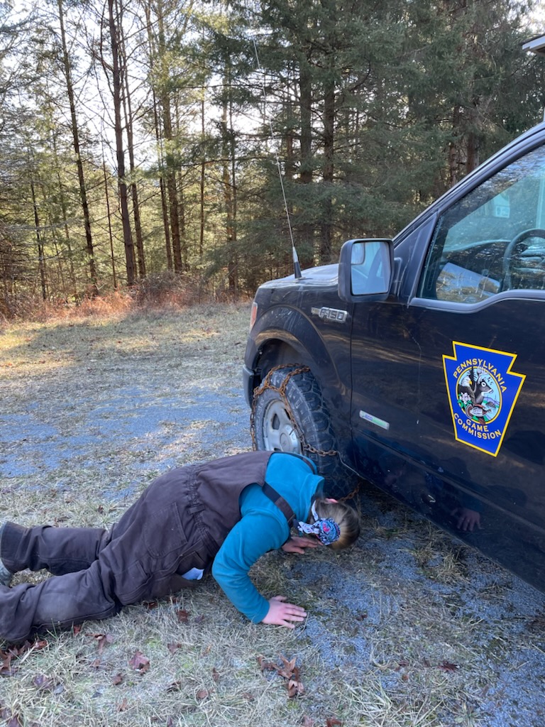 Person laying on ground putting on tire chains