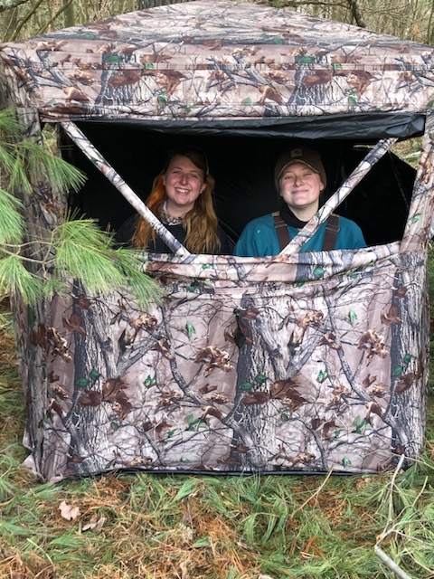 2 crew members sitting in a ground blind looking out the window