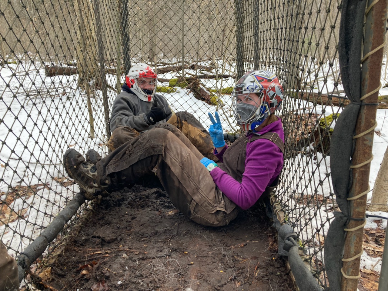 2 people sitting in Clover trap in the mud