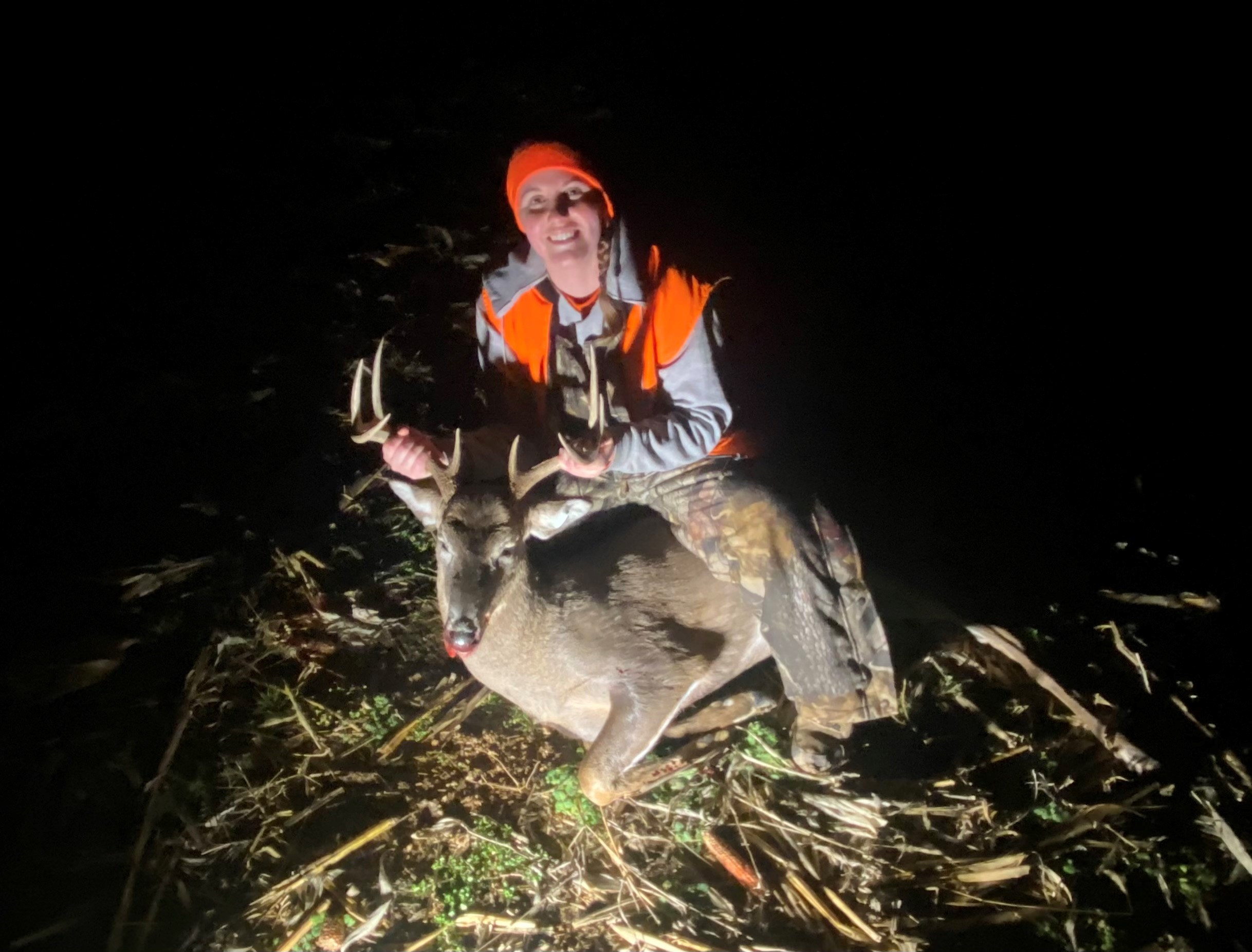 hunter holding head up of a harvest buck in field